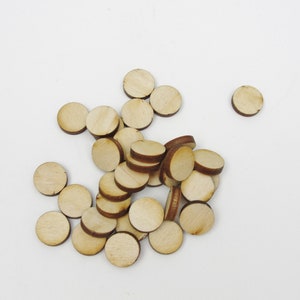 May include: A pile of round, wooden craft circles in a natural wood color. The circles are about 1 inch in diameter and have a slightly rough texture.