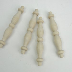 May include: Four unfinished wooden furniture legs with a turned design. Each leg has three decorative rings.