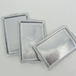 May include: Three silver baking sheets, each with a slightly different shape and size.