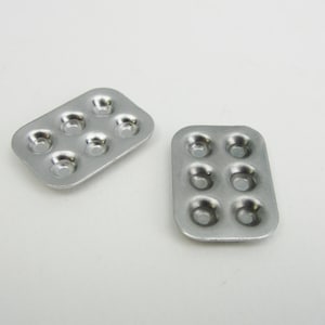 May include: Two silver baking pans with six round depressions each. The pans are made of metal and have a shiny finish.