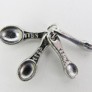 May include: A set of three silver measuring spoons with the measurements 1 tbsp, 1 tsp, and 1/4 tsp.