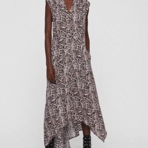 May include: Sleeveless maxi dress with a V-neckline and a snakeskin pattern in shades of gray and beige. The dress has a flowing, asymmetrical hemline and is paired with black combat boots.