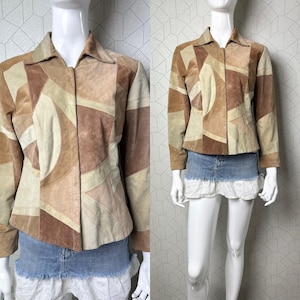 Peut inclure: Une veste en daim marron et beige avec un motif géométrique en patchwork. La veste a une fermeture éclair et un col.