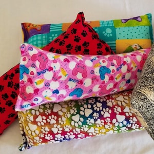 May include: A collection of six catnip toys, each with a different colorful fabric pattern. The toys are made of soft fabric and are filled with catnip. The patterns include paw prints, hearts, and a cat face.