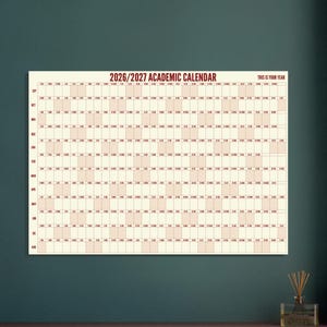 Könnte beinhalten: Ein akademischer Wandkalender für 2026/2027 mit cremefarbenem Hintergrund und dunkelroter Schrift. Das Raster zeigt die Monate von September bis August mit abwechselnd hellrosa und weißen Spalten für die Tage und dem Text THIS IS YOUR YEAR.
