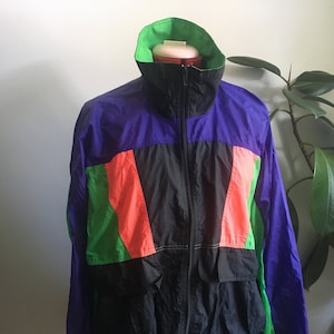 May include: A black, green, purple and orange colour block windbreaker jacket with a zip closure.