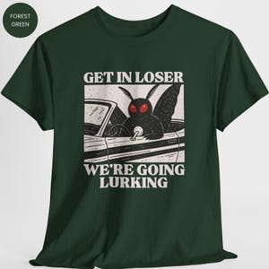 May include: Forest green t-shirt featuring a black moth driving a car with the text "GET IN LOSER WE'RE GOING LURKING" in white. The moth has red eyes and is in the driver's seat.