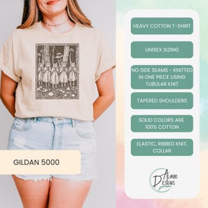 May include: A beige t-shirt with a black and white illustration of a group of figures in a forest. The shirt is made of heavy cotton and has a unisex fit. The text "GILDAN 5000" is printed on the bottom of the shirt. The text "HEAVY COTTON T-SHIRT", "UNISEX SIZING", "NO SIDE SEAMS - KNITTED IN ONE PIECE USING TUBULAR KNIT", "TAPERED SHOULDERS", "SOLID COLORS ARE 100% COTTON", "ELASTIC, RIBBED KNIT, COLLAR", and "LAVIO DESIGNS" is printed on the right side of the image.