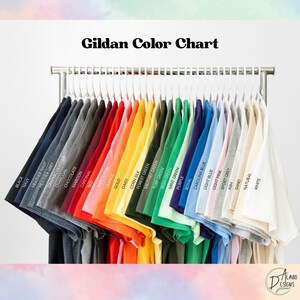 May include: A color chart displaying a variety of Gildan t-shirts in various colors, including black, navy, red, orange, and green. The shirts are hanging on a metal rack with white hangers. The text "Gildan Color Chart" is at the top.