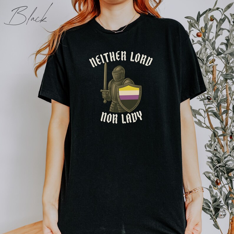 May include: Black t-shirt featuring the text "NEITHER LORD NOR LADY" above an illustration of a knight holding a sword and shield with the non-binary pride flag colors. The word "Black" is written in cursive in the upper left corner.