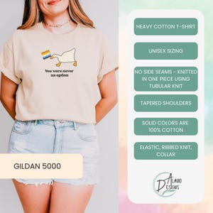 Op de afbeelding: Een beige T-shirt met een witte eend die een regenboogvlag vasthoudt en de tekst "You were never an option". Het shirt is een Gildan 5000, een zwaar katoenen T-shirt met unisex maatvoering, zonder zijnaden, gebreid met een buisvormige constructie, taps toelopende schouders en een elastische geribbelde kraag.