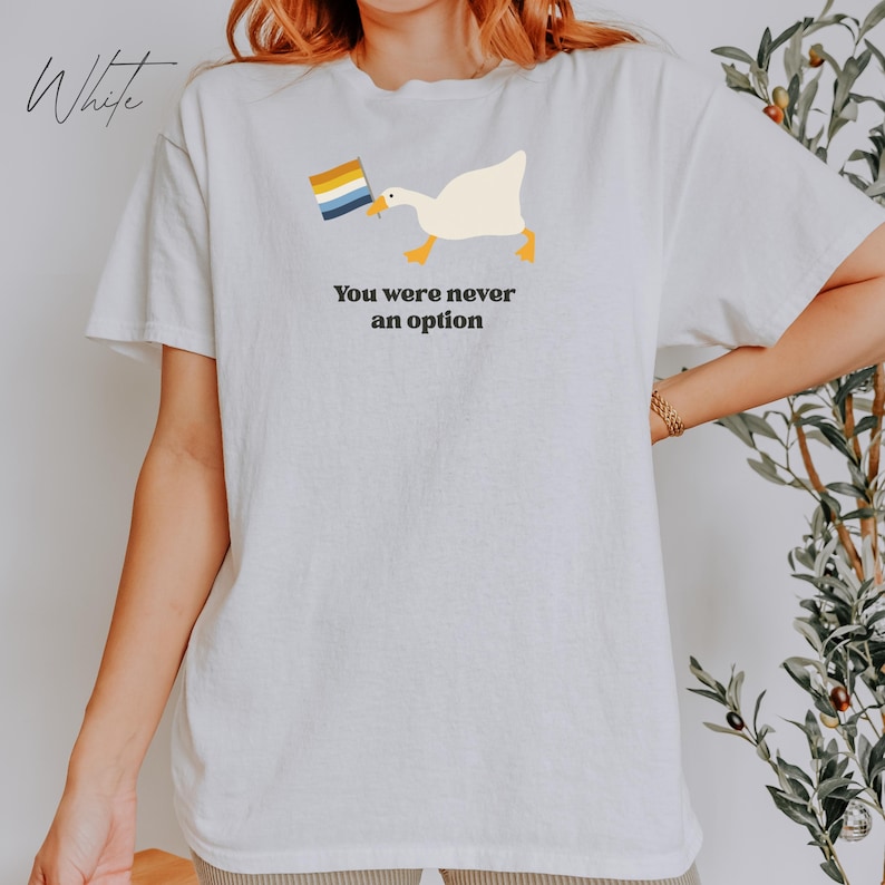 Op de afbeelding: Wit T-shirt met een afbeelding van een gans die een regenboogvlag draagt en de tekst "You were never an option".
