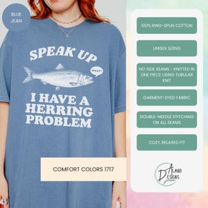 以下が含まれることがあります： 「SPEAK UP」の文字と魚のイラスト、そして「I HAVE A HERRING PROBLEM」というフレーズがプリントされた、ブルーのジーンズカラーのTシャツ。リラックスフィット、ユニセックスサイズで、100％リングスパンコットン製です。
