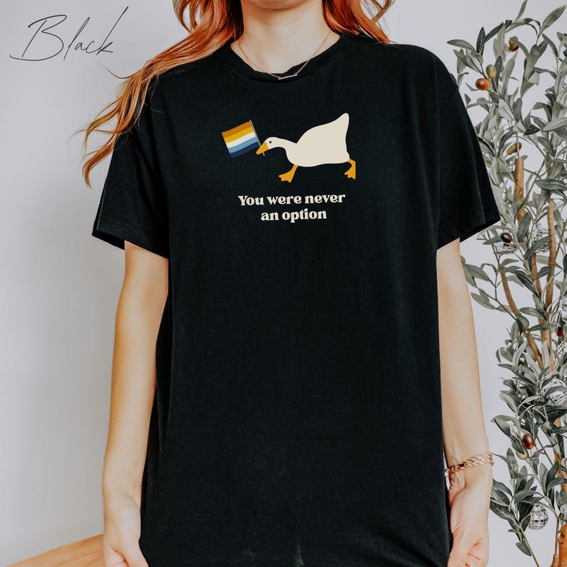 Op de afbeelding: Zwart T-shirt met een witte gans die een regenboogvlag vasthoudt en de tekst "You were never an option".