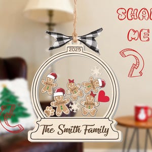 May include: A wooden Christmas ornament shaped like a snow globe, featuring gingerbread people with names, a red heart, and snowflakes. The ornament is adorned with a black and white checkered bow and the text "The Smith Family" and "2025".