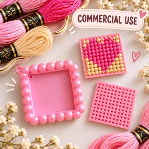 Pode incluir: Uma moldura quadrada rosa com borda de contas, um inserto de grade quadrado rosa correspondente e um inserto quadrado com um padrão de coração em ponto cruz rosa e dourado. A imagem inclui o texto COMMERCIAL USE e fios de bordar rosa.