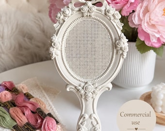 May include: An off-white oval hand mirror frame featuring intricate relief carvings of roses and a bow at the top. The center of the frame contains a fine mesh grid. The handle is also decorated with rose carvings and wood grain textures.