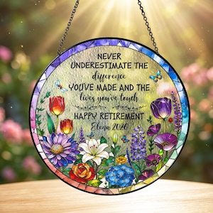 May include: A round, stained-glass retirement decoration with a floral design and the text "NEVER UNDERESTIMATE THE difference YOU'VE MADE AND THE lives you've touch HAPPY RETIREMENT Elena 2026". The decoration is suspended by a chain.