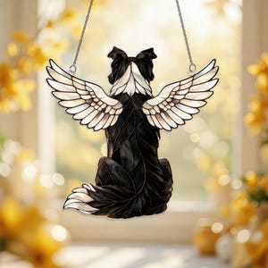 May include: A black and white dog-shaped suncatcher with angel wings, hanging from a silver chain. The dog is depicted from the back, with its head and tail in white. The wings are white with brown accents.
