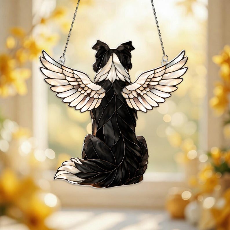 May include: A black and white dog-shaped suncatcher with angel wings, hanging from a silver chain. The dog is depicted from the back, with its head and tail in white. The wings are white with brown accents.