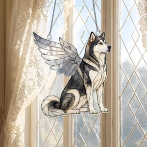 May include: A stained glass suncatcher depicting a husky dog with large, translucent wings. The dog features black, grey, and white segments with dark outlines. The piece is suspended by a thin metal chain, showcasing a detailed canine silhouette.