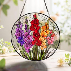 May include: A round stained glass window featuring a vibrant arrangement of gladiolus flowers in shades of purple, red, orange, and pink. The flowers are set against a light background, framed by a black metal border and hanging chain.
