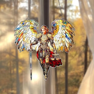 May include: Stained glass depiction of an angel with outstretched wings. The angel is clad in golden armor and holds a sword and scales. The wings are multi-colored, with hues of yellow, blue, and red. The artwork is suspended by a chain.