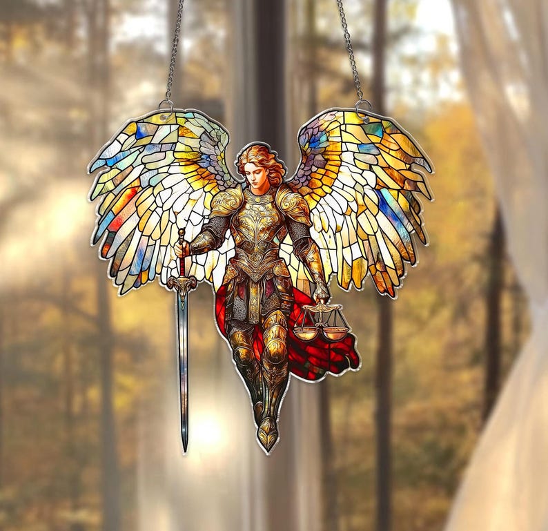 May include: Stained glass depiction of an angel with outstretched wings. The angel is clad in golden armor and holds a sword and scales. The wings are multi-colored, with hues of yellow, blue, and red. The artwork is suspended by a chain.