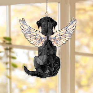 May include: A black dog silhouette with stained glass angel wings. The dog is sitting, facing away from the viewer. The wings are iridescent with a variety of colors. The suncatcher hangs from a chain.