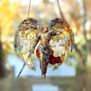 May include: Stained glass angel with golden armor, holding a sword and scales. The angel has large, colorful wings with shades of yellow, orange, and blue. The artwork is suspended by a chain.