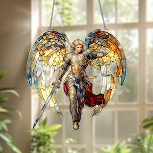 May include: A stained glass-style angel with large, colorful wings. The angel is depicted in golden armor, holding a sword and scales. The wings feature a mosaic of yellow, orange, and blue hues, creating a vibrant and detailed design. The artwork is suspended by a chain.