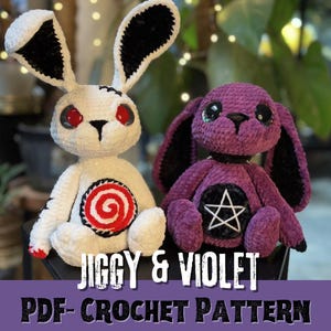 May include: Crochet pattern for two amigurumi toys: a white rabbit with black ears and a purple dog with black ears. The rabbit has a red and white swirl on its chest and the dog has a black pentagram on its chest. The pattern is called "Jiggy & Violet" and is a PDF crochet pattern.