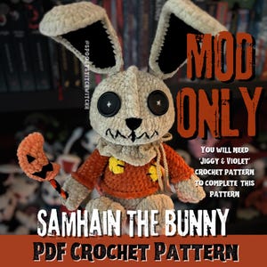 May include: A crocheted Samhain the Bunny, featuring a cream-coloured head and ears with black details. It has large black button eyes and a stitched mouth. The bunny is dressed in an orange sweater and holds a pumpkin-shaped accessory. The image includes text that reads "MOD ONLY" and "SAMHAIN THE BUNNY PDF CROCHET PATTERN."