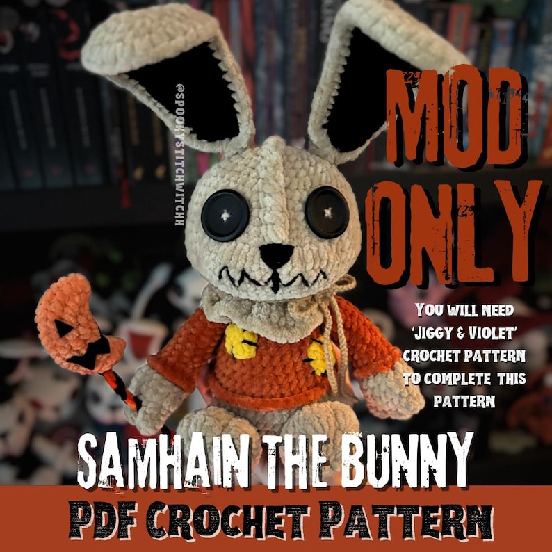 May include: A crocheted Samhain the Bunny, featuring a cream-coloured head and ears with black details. It has large black button eyes and a stitched mouth. The bunny is dressed in an orange sweater and holds a pumpkin-shaped accessory. The image includes text that reads "MOD ONLY" and "SAMHAIN THE BUNNY PDF CROCHET PATTERN."