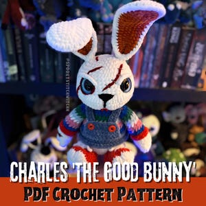 Può includere: Un coniglio all'uncinetto fatto a mano con testa bianca, cicatrici rosse e occhi blu. Il coniglio indossa un maglione a righe e una salopette di jeans. Il testo "CHARLES 'THE GOOD BUNNY' PDF CROCHET PATTERN" è visualizzato in basso nell'immagine.
