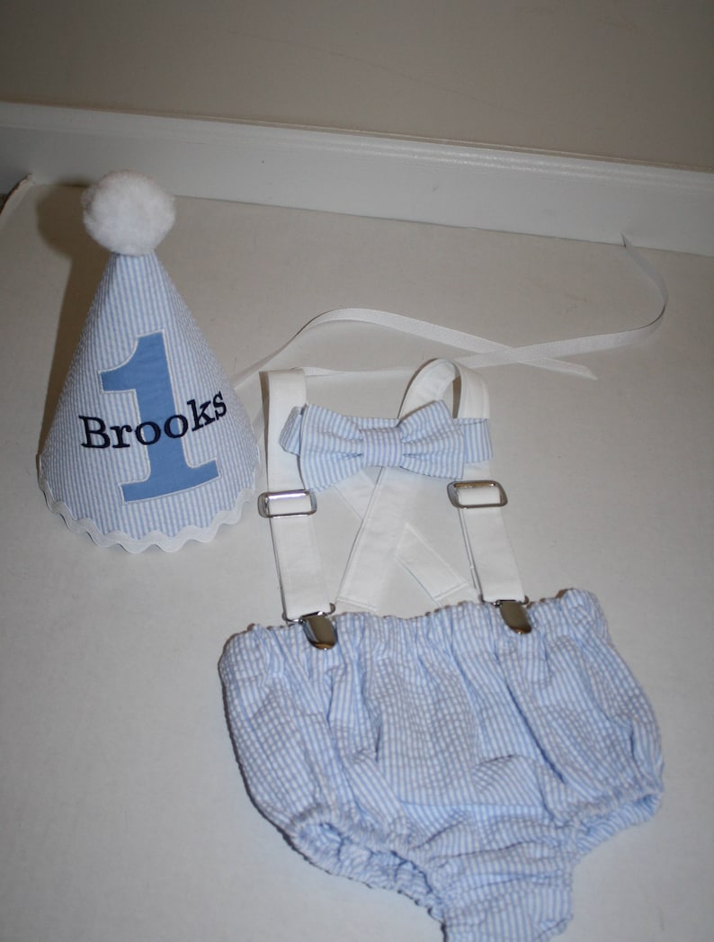 Boys first birthday cake smash outfit. Birthday hat, bow tie, suspenders and diaper cover available.  Personalized birthday hat with number and name. Baby Blue seersucker fabric with white suspenders and hat accents.