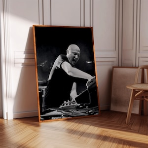 Peut inclure: Impression encadrée en noir et blanc d'un homme jouant du clavier. L'homme, vêtu d'un t-shirt noir, se penche sur l'instrument. L'impression est dans un cadre en bois et repose contre un mur blanc.