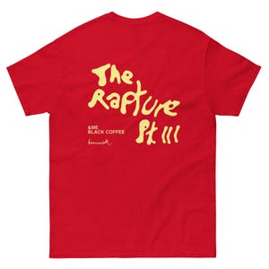 Może przedstawiać: Czerwony T-shirt z krótkim rękawem z żółtym nadrukiem, na którym widnieje napis "The Rapture Pt III & ME BLACK COFFEE homemade".