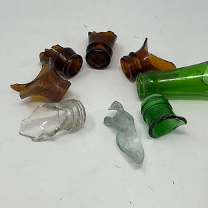 May include: A collection of broken glass bottles in various colors, including green, brown, and clear. The pieces are sharp and should be handled with care.