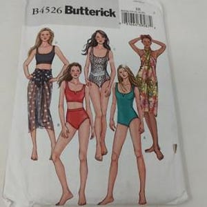 May include: A white Butterick sewing pattern envelope, B4526, featuring illustrations of women in swimwear and cover-ups. The designs include a bikini, a one-piece swimsuit, and a sarong. The illustrations are in color.