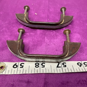 May include: Two brown plastic cabinet drawer pulls with silver trim and screws. The pulls are approximately 2.5 inches long.
