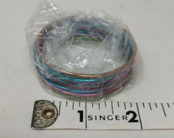 May include: A stack of colorful metal bangles in a clear plastic bag. The bangles are in shades of blue, pink, and green. A measuring tape is next to the bangles.