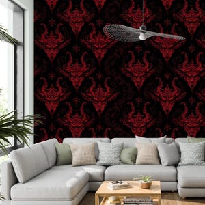 May include: A living room featuring a black and red patterned wallpaper with a repeating devil-like design. A white sectional sofa with several cushions is in front of the wall. A ceiling fan hangs from the ceiling.
