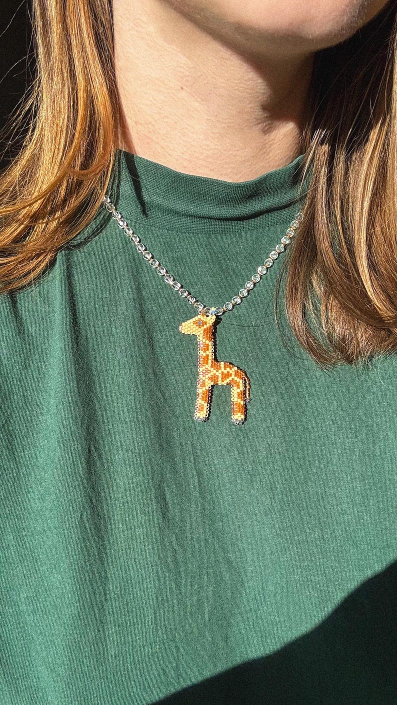 May include: A white ceramic mug with a black handle and the text "But First, Coffee" in a bold, black font. The mug is set against a blurred background, suggesting a cozy setting. The mug appears to be approximately 4 inches tall.