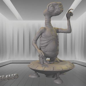 Pode incluir: Uma escultura cinzenta do personagem extraterrestre E.T. A figura está em pé sobre uma base circular com três pernas. O alienígena está levantando a mão direita. A palavra "MERALED" está na parte inferior.