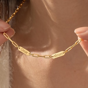 May include: Gold chain necklace with two rectangular name tags, one with the name "Omar" and the other with the name "Miriam".
