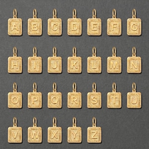 May include: A collection of gold-colored rectangular pendants, each engraved with a different letter of the alphabet from A to Z. The pendants have a sunburst design around the letters and a small loop at the top for a chain.