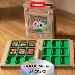 May include: A beige plastic storage case shaped like a Nintendo Game Boy cartridge, featuring a holographic Pokémon Rowlet sticker. The open case reveals a green interior with slots for six Nintendo Switch game cartridges and empty spaces.