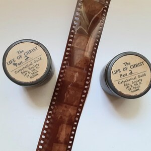 May include: Two black film reels with white labels. The labels read "The Life of Christ" with "Part 2" and "Part 3" respectively. The labels also include the text "Catechetical Guild Edu. Society 147 E. 5th St. ST. PAUL MINN."