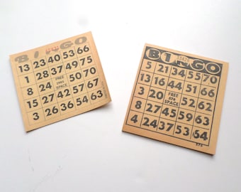 May include: Two brown paper bingo cards with black numbers. The top card has the numbers 13, 23, 40, 53, 66, 1, 28, 37, 49, 75, 8, 24, 50, 70, 15, 27, 42, 57, 67, 3, 26, 36, 54, 63. The bottom card has the numbers 5, 21, 34, 55, 70, 13, 16, 44, 51, 66, 3, 20, 52, 62, 8, 27, 45, 59, 63, 4, 24, 37, 53, 64. Both cards have the word "Bingo" printed on them.